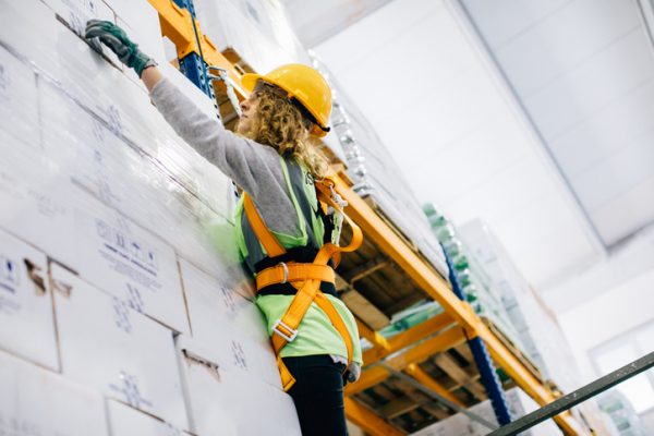 young industrial high climber woman working and checking boxes in shipping manufacturing facility warehouse