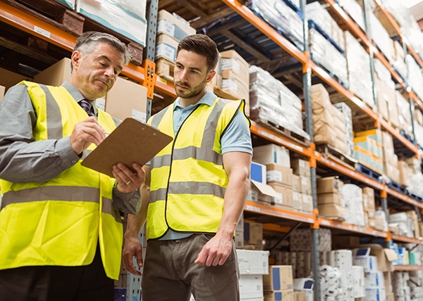 a senior team leader in a warehouse talking to a worker